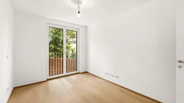 Helles Zimmer mit Holzboden und französischem Balkon, der viel Licht spendet.