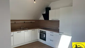 Moderne Küche mit weißen Schränken, Holzoptik-Arbeitsplatten und Dachschräge.
