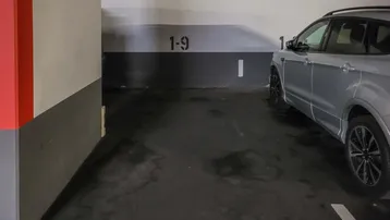 Einzelner Stellplatz in einer Tiefgarage mit markierten Parkflächen und einem silbernen Auto.