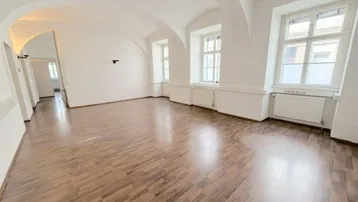 Helles, leeres Zimmer mit Holzboden und gewölbter Decke, bereit zur individuellen Gestaltung.