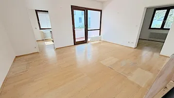 Helles Wohnzimmer mit Parkettboden und Zugang zum Balkon, bereit zur individuellen Gestaltung.