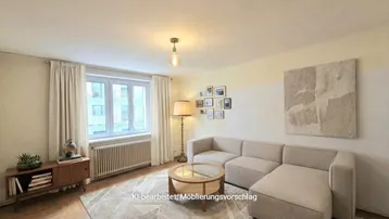 Helles Wohnzimmer mit modernem Sofa, Holzboden und einem Fenster, das viel Tageslicht hereinlässt.