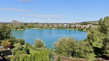 Weitläufiger Blick auf einen ruhigen See mit umliegender Wohnbebauung und viel Grün.