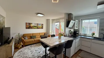 Geräumiger Wohn- und Essbereich mit integrierter Küche, Holzboden und moderner Deckenbeleuchtung.