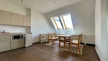 Helle Küche mit Essbereich, Dachschrägen und Holzboden, beleuchtet durch Dachfenster.