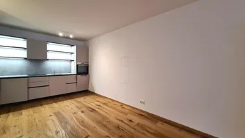 Heller Raum mit moderner Einbauküche und Holzboden, bereit für die individuelle Gestaltung.