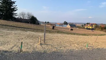 Leeres Grundstück mit Schotterweg und Blick auf die umliegende Landschaft und Häuser.