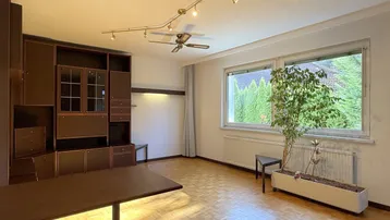 Helles Wohnzimmer mit Parkettboden, großem Fenster und integriertem Regal.