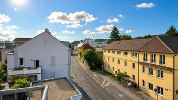 Sonnige Aussicht über eine städtische Straße mit umliegenden Gebäuden und blauem Himmel.