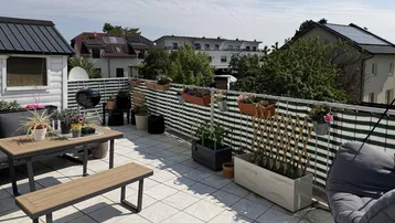 Geräumige Dachterrasse mit Fliesenboden, Grillbereich und Blick auf die Umgebung.