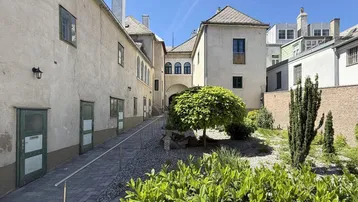 Blick in einen gepflasterten Innenhof mit üppiger Bepflanzung und historischen Gebäudefassaden.