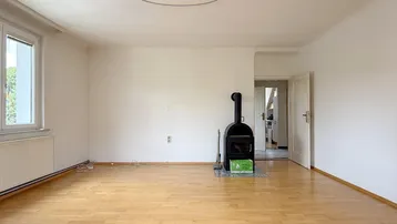 Geräumiges Wohnzimmer mit Holzofen, Parkettboden und hellem Anstrich, bereit zur Gestaltung.