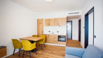 Heller Wohn-Essbereich mit integrierter Küchenzeile, Holzboden und modernen Möbeln in Gelb.