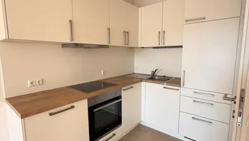 Moderne Einbauküche in Weiß mit Holz-Arbeitsplatte und integrierten Geräten in neuwertigem Zustand.