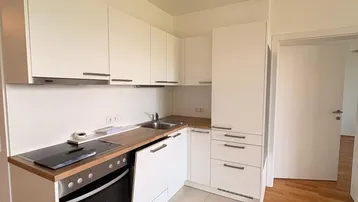 Moderne Einbauküche in Weiß mit Holzarbeitsplatte und integrierten Geräten, ideal für den täglichen Gebrauch.