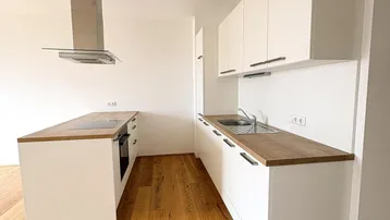 Moderne Küche mit weißen Schränken, Holzarbeitsplatten, Kochinsel und Dunstabzugshaube.