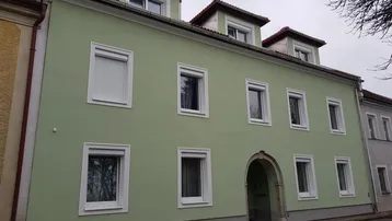 Das Gebäude präsentiert sich mit einer frisch gestrichenen hellgrünen Fassade und Dachgauben.