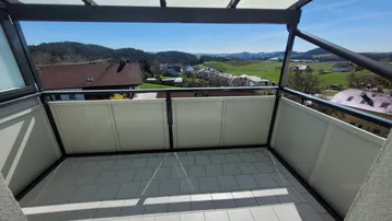 Geräumiger Balkon mit Fliesenboden und Überdachung, bietet weiten Blick über die Landschaft.