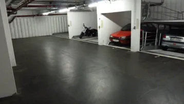 Geräumige Tiefgarage mit mechanischen Doppelparkern, bietet Platz für Autos und ein Motorrad auf robustem Betonboden.