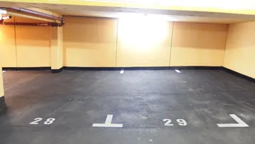 Gut gepflegte Tiefgarage mit markierten Stellplätzen und gelben Wänden.