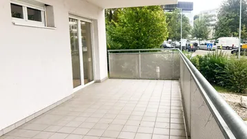 Geräumiger Balkon mit Fliesenboden und Metallgeländer, bietet Blick auf die Umgebung.