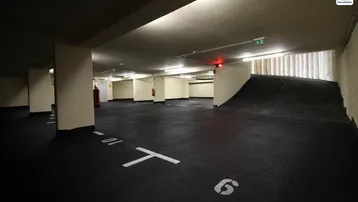 Geräumige Tiefgarage mit markierten Stellplätzen, Betonpfeilern und einer Auffahrtsrampe.