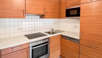 Funktionale Einbauküche mit Holzfronten, modernen Geräten und Fliesenboden.