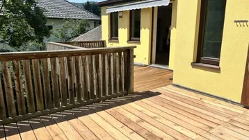 Große Holzterrasse mit Geländer und Blick auf die umliegende Natur, ideal für Entspannung im Freien.