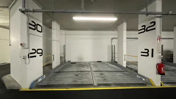 Tiefgaragenstellplatz mit automatischem Parksystem für zwei Fahrzeuge in einem modernen Gebäude.