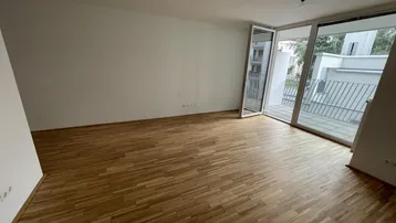 Helles Wohnzimmer mit Parkettboden und Zugang zu einem Balkon, bereit für die individuelle Einrichtung.