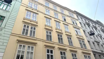 Klassische Fassade eines Mehrfamilienhauses mit vielen Fenstern in hellem Gelbton.