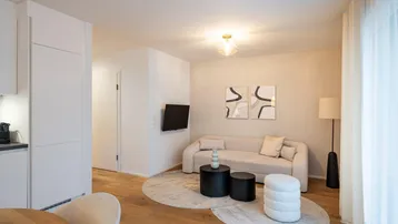 Helles Wohnzimmer mit modernem Sofa, Couchtischen und Holzboden, offen zum Essbereich.
