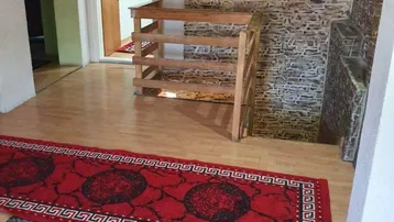 Wohnbereich mit Holzboden, dekorativer Wandverkleidung und Teppichen, der zu einem weiteren Raum führt.