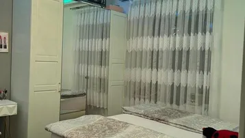 Helles Schlafzimmer mit Doppelbett, Kleiderschrank und dekorativer Deckenbeleuchtung.