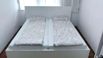 Helles Schlafzimmer mit einem großen Doppelbett, weißen Vorhängen und Holzboden.