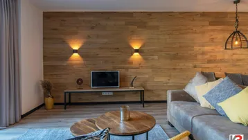 Gemütliches Wohnzimmer mit Holzwandverkleidung, bequemer Couch und indirekter Beleuchtung.
