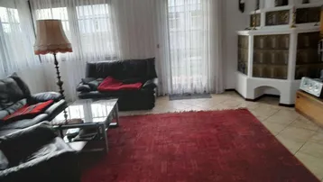 Gemütliches Wohnzimmer mit traditionellem Kachelofen, Fliesenboden und Zugang zum Außenbereich.