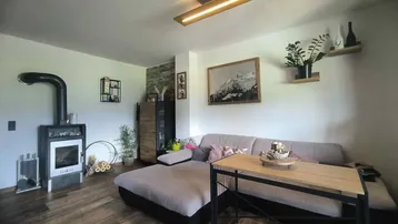 Gemütliches Wohnzimmer mit großem Sofa, Holzboden und einem modernen Holzofen für behagliche Wärme.