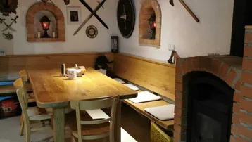 Das rustikale Esszimmer mit Kamin, Holztisch und Holzbalkendecke.