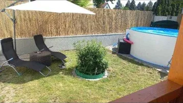 Gartenbereich mit einem Aufstellpool, Liegestühlen und Sonnenschirm für entspannte Stunden.