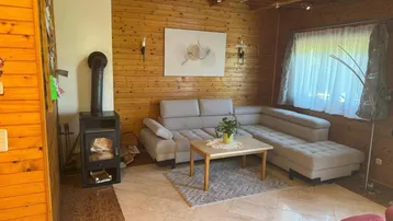 Gemütliches Wohnzimmer mit Holzvertäfelung, Kaminofen und bequemer Sitzecke.