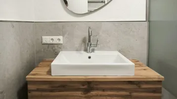 Modernes Badezimmer mit schwebendem Holzwaschtisch, Aufsatzwaschbecken und ovalem Spiegel.