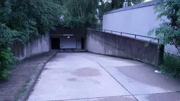 Einfahrt zu einer Tiefgarage oder einem Kellerbereich mit Betonwänden und Rampe.