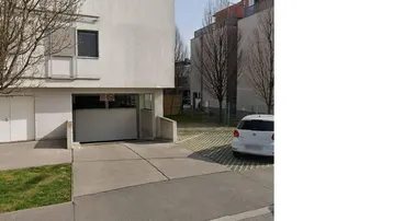 Modernes Gebäude mit Tiefgaragenzufahrt und Außenstellplatz auf gepflegtem Gelände.