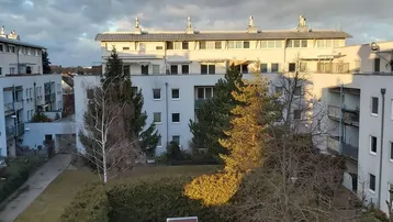 Blick von oben auf einen Innenhof mit Spielplatz und umliegenden Wohngebäuden unter bewölktem Himmel.
