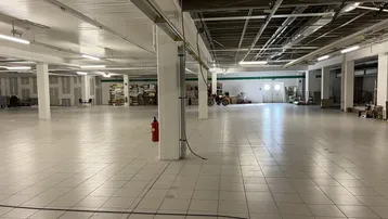 Geräumiger Gewerbebereich mit quadratischen Bodenfliesen, vielen Säulen und offener Deckenkonstruktion.