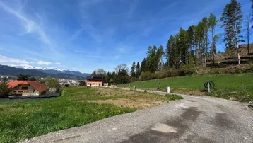 Panoramablick auf die umliegende Landschaft mit schneebedeckten Bergen, grünen Hügeln und einer Stadt in der Ferne.
