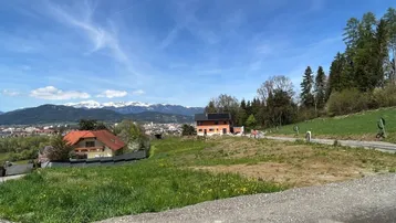 Panoramablick auf die umliegende Landschaft mit Häusern und schneebedeckten Bergen unter blauem Himmel.