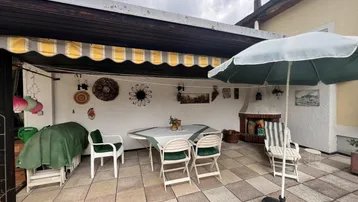 Überdachte Terrasse mit Essbereich, Kamin und Markise für gemütliche Stunden im Freien.