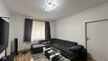 Helles Wohnzimmer mit modernem Ecksofa, Teppich und Laminatboden, ideal zum Entspannen.
